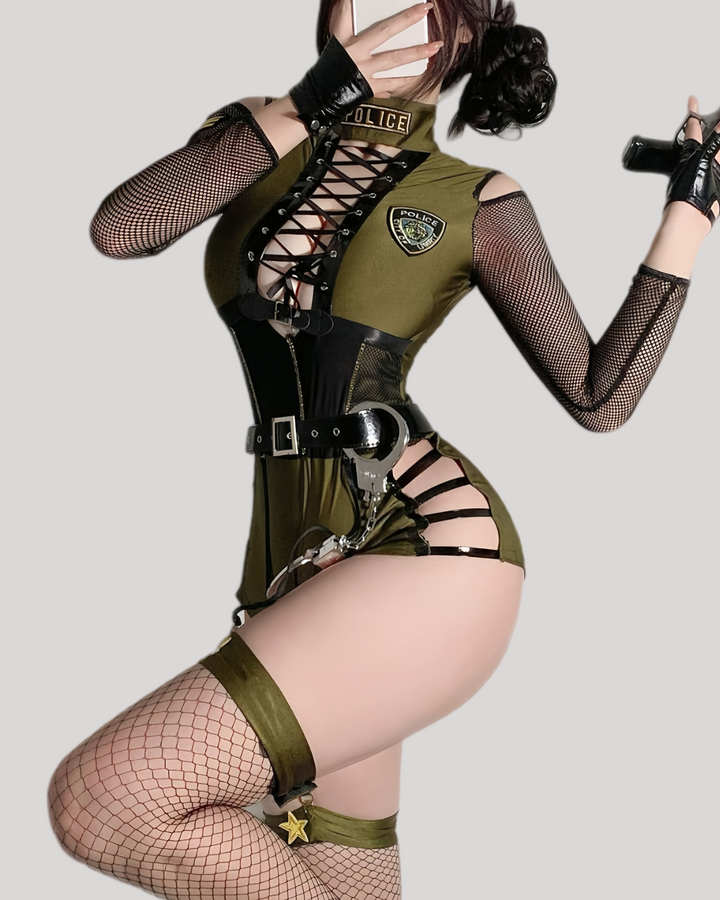 Person wearing a green police-themed costume with black straps and fishnet stockings on a gray background.