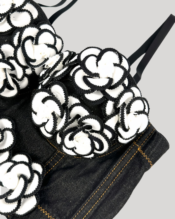 Front view of black denim corset with white floral appliqués