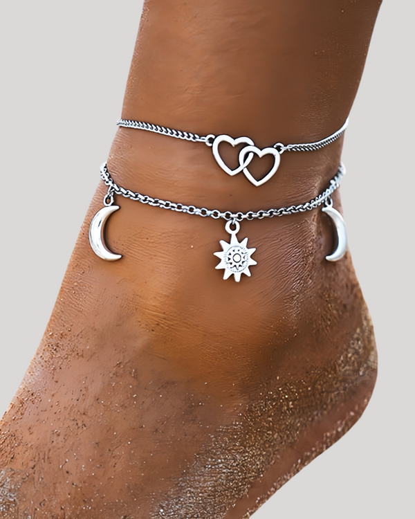 Silver anklets with heart, moon, and star charms on a person's ankle