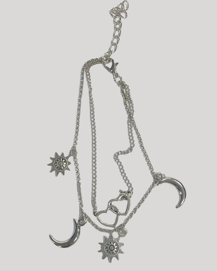 Product flat lay of silver celestial anklet with heart and moon charms