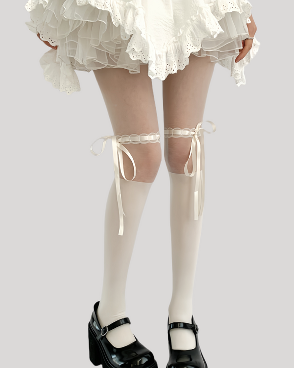 Cream thigh-high tights with side satin bows and ruffle trim styled with white ruffled skirt and black Mary Jane platform heels
