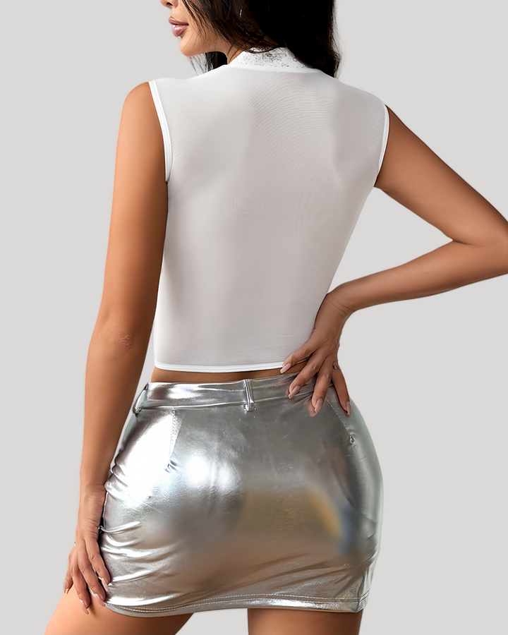 Person wearing a white sleeveless top and silver metallic skirt on a plain background