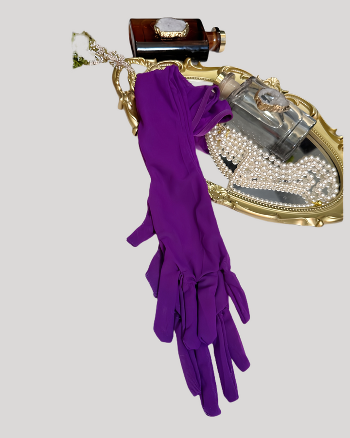 Purple gloves with a gold clutch and perfume bottle on a light gray background