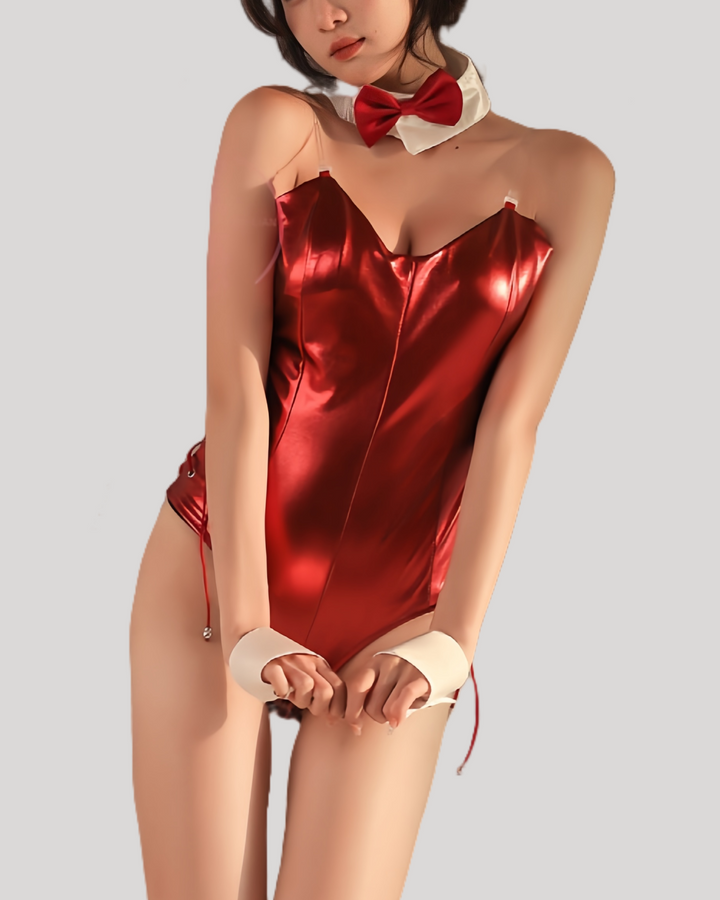 Model wearing a red patent leather bunny bodysuit with attached tail, clear shoulder straps, matching black bunny ears headband, white collar with black bow tie, and cuff wristbands.