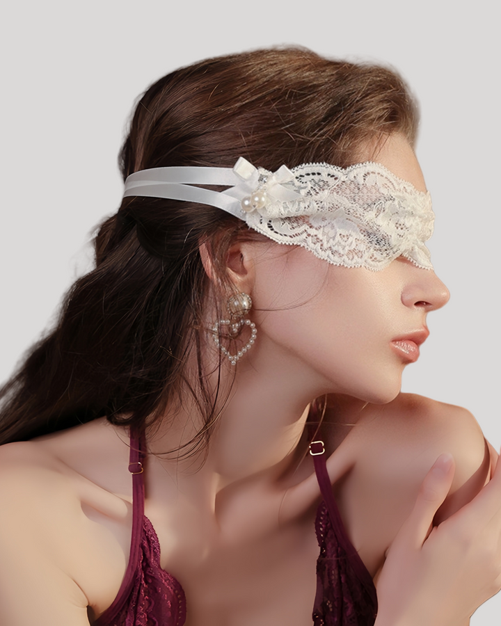 Model wearing white lace blindfold with bow and pearls