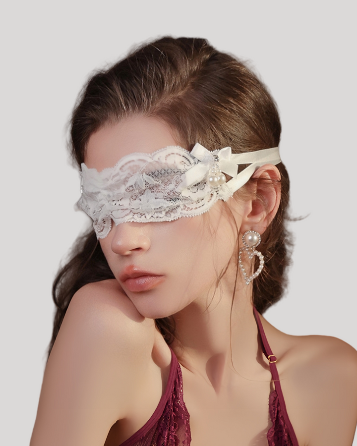 Model wearing white lace blindfold with bow and pearls