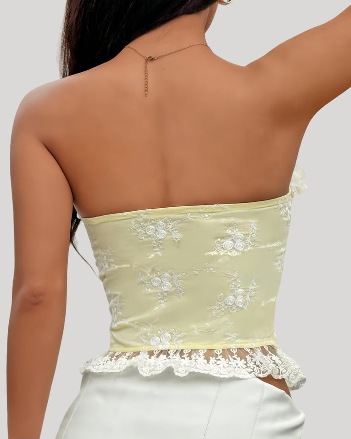 Woman wearing yellow floral embroidered corset with lace-up front and 3D flower bustline