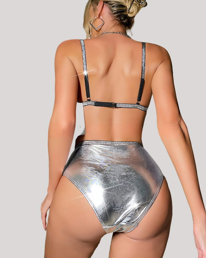 Back view of model showcasing adjustable metallic bra straps and high-cut silver bottoms with fringe accents.