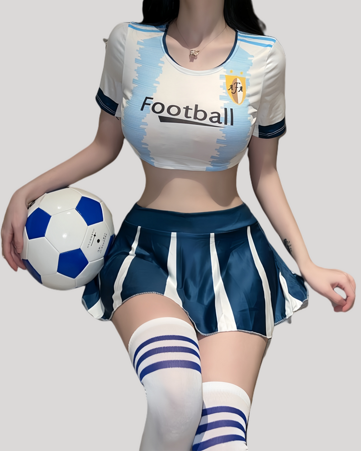Model in sky-blue cropped football top and pleated mini skirt holding a soccer ball.
