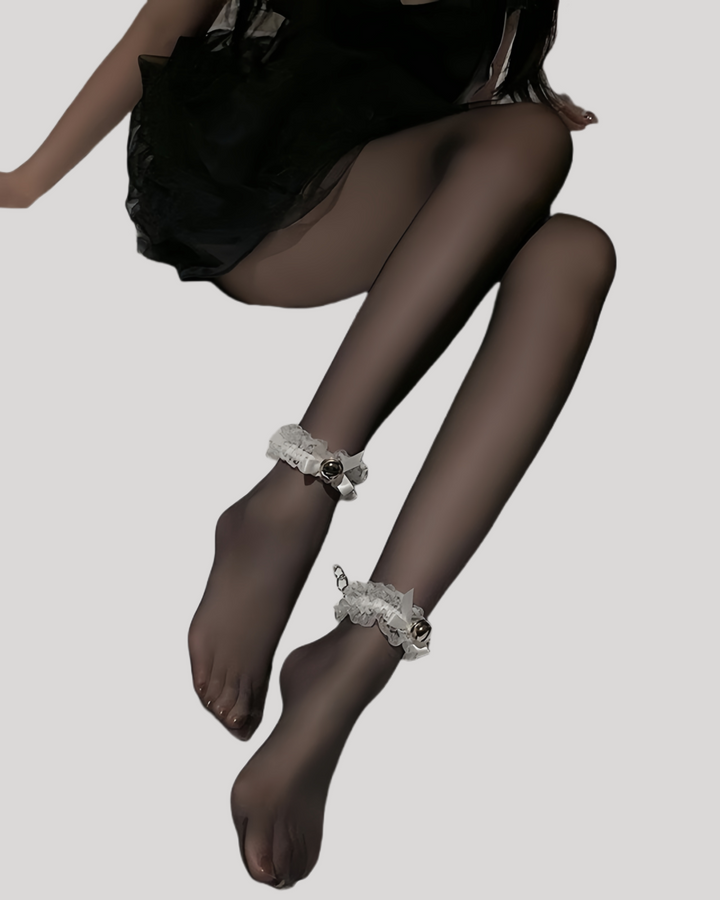 Model in white lace ankle cuff set featuring satin bows and silver bells