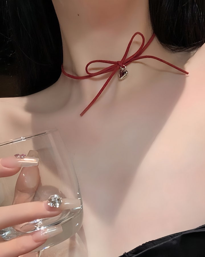 Woman wearing red velvet bow choker with heart charm